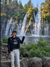 Person posing in front of a waterfall with scenic background in Stellar Moto Brand Utopia Motorcycle jeans 