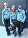 Three people posing together in front of a gray wall in their Stellar Horizon moto jean jackets