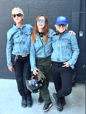 Three people posing together in front of a gray wall in their Stellar Horizon moto jean jackets