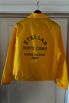 Yellow jacket with 'Stellar Moto Camp' text on a white door