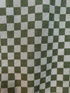 A short-sleeved camp shirt with a checkered pattern in British Racing Green, displayed on a wooden background.