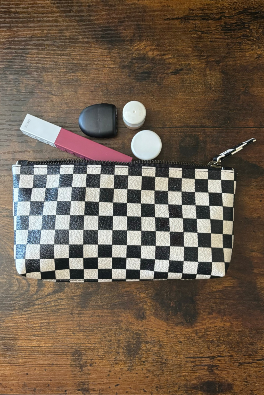 Stellar Checkered leather makeup pouch with makeup items on a wooden surface