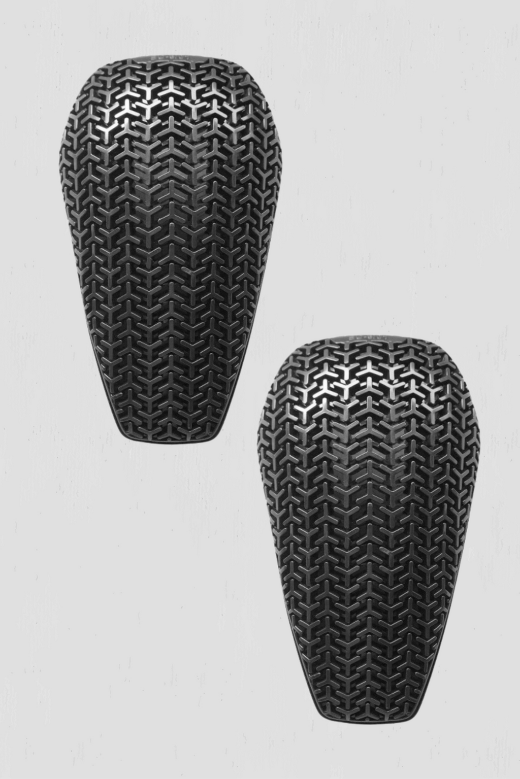 Two black elbow and knee guards with textured surface on a light gray background